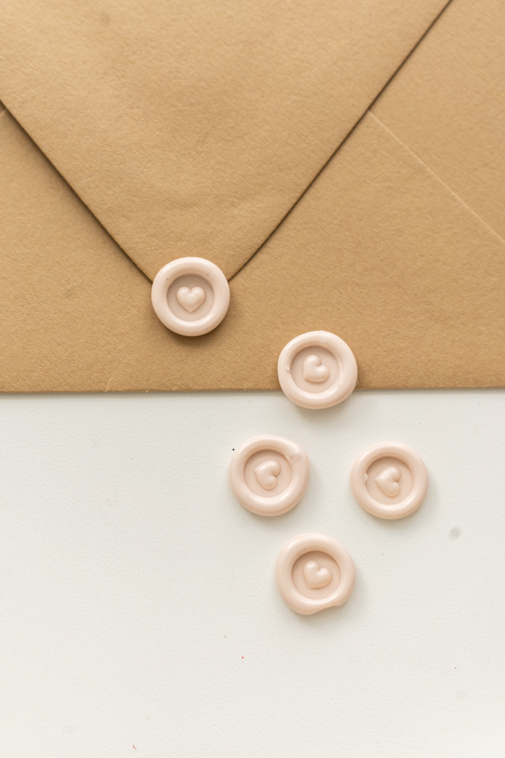5 mini blush wax seals with a 3D heart design on a kraft envelope and white surface