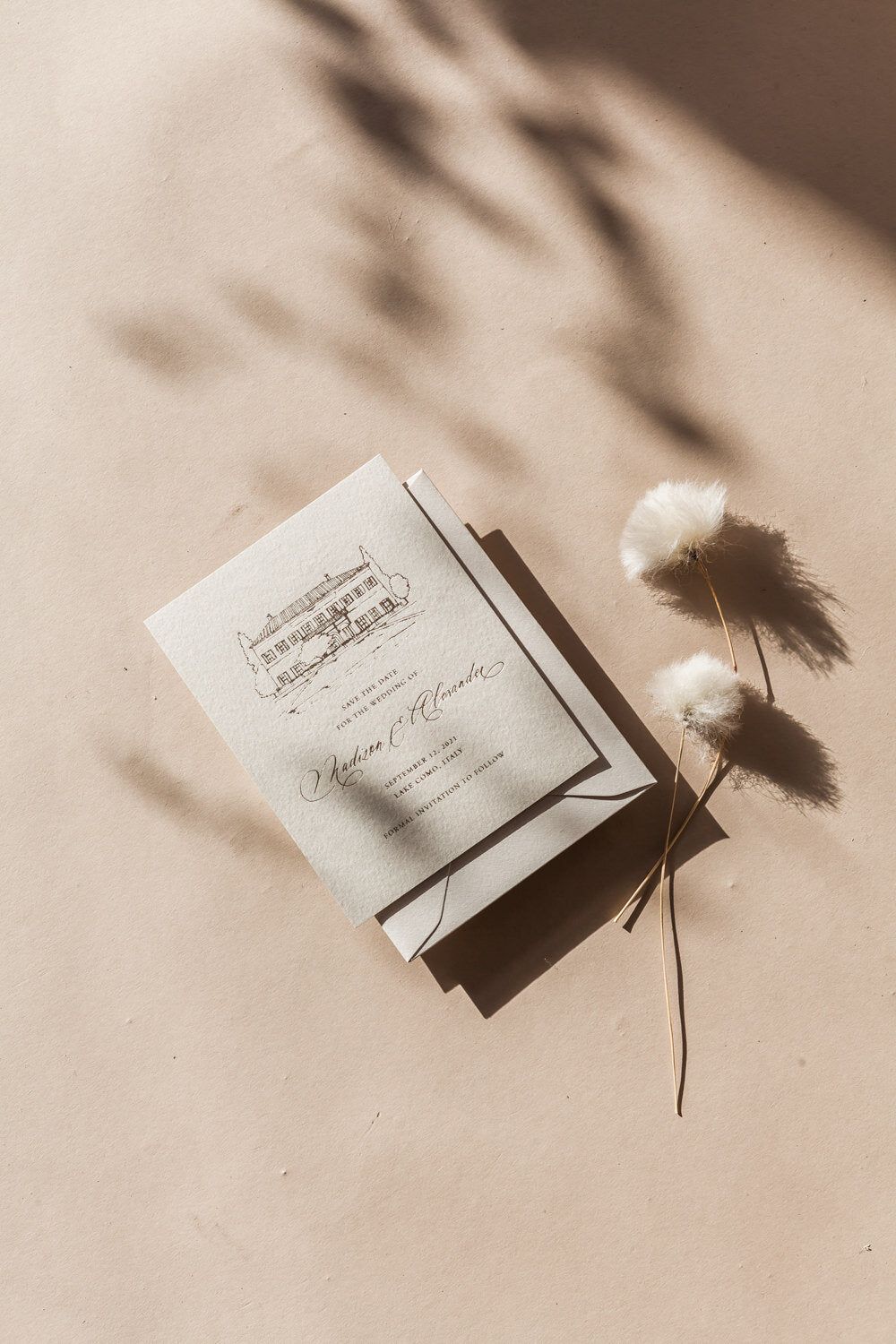 Elegant save the date card with venue illustration and calligraphy names on textured paper, neutral wedding stationery