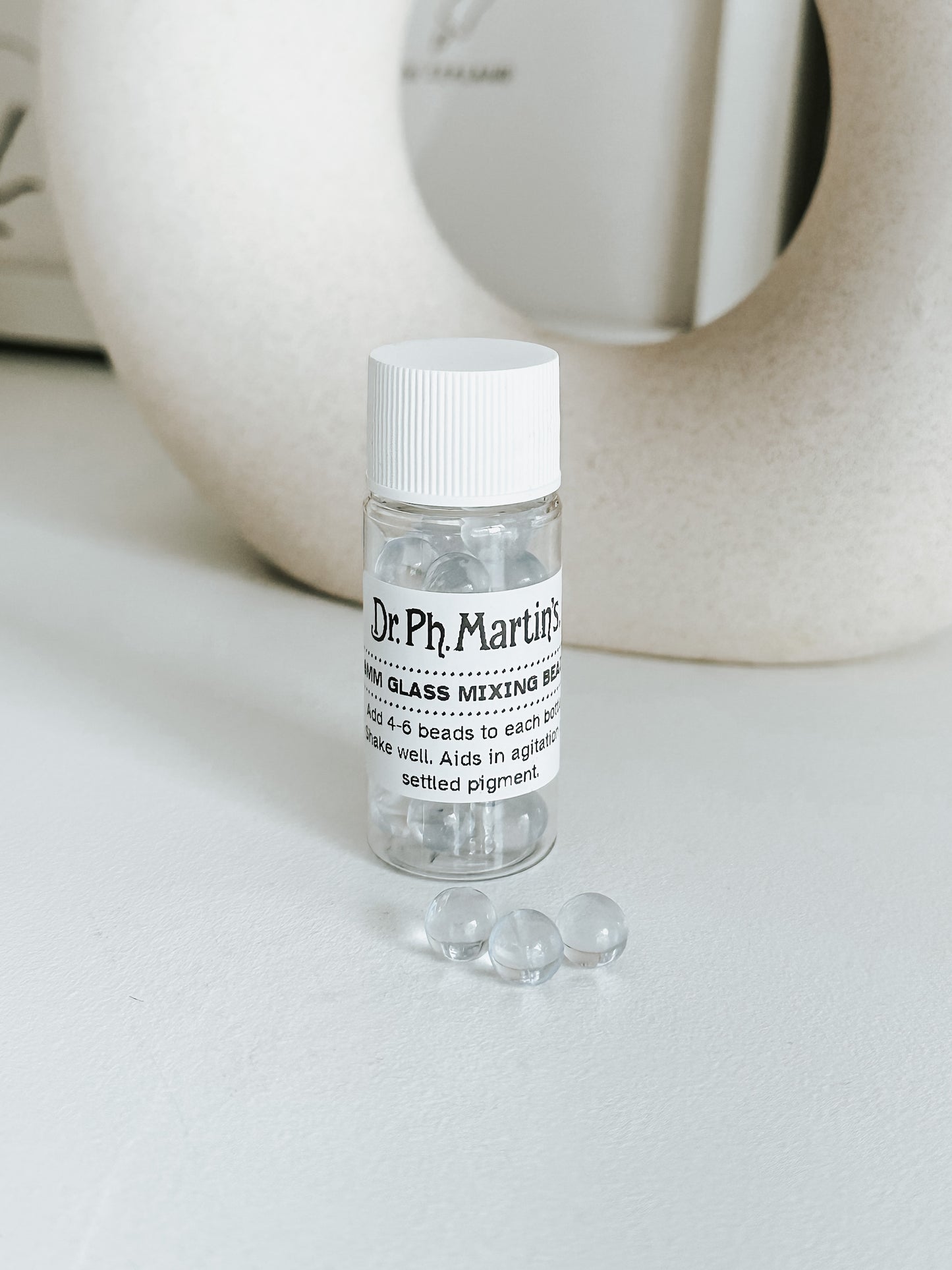 Dr. Ph. Martin's 4mm glass mixing beads in a clear bottle, shown with loose beads, ideal for blending settled pigments