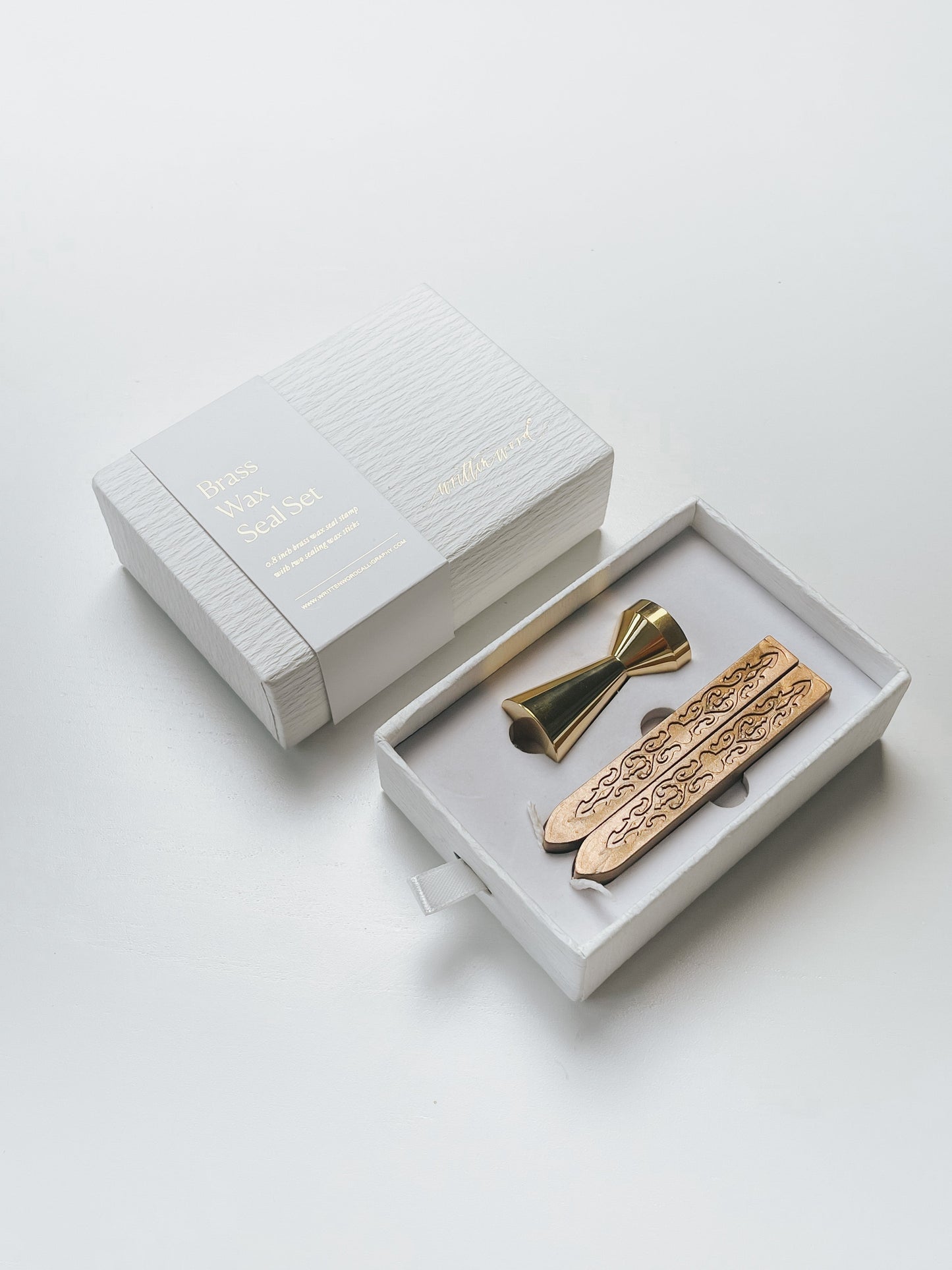 Elegant brass wax seal set with two gold wax sticks in luxury packaging, styled elegantly on a white surface