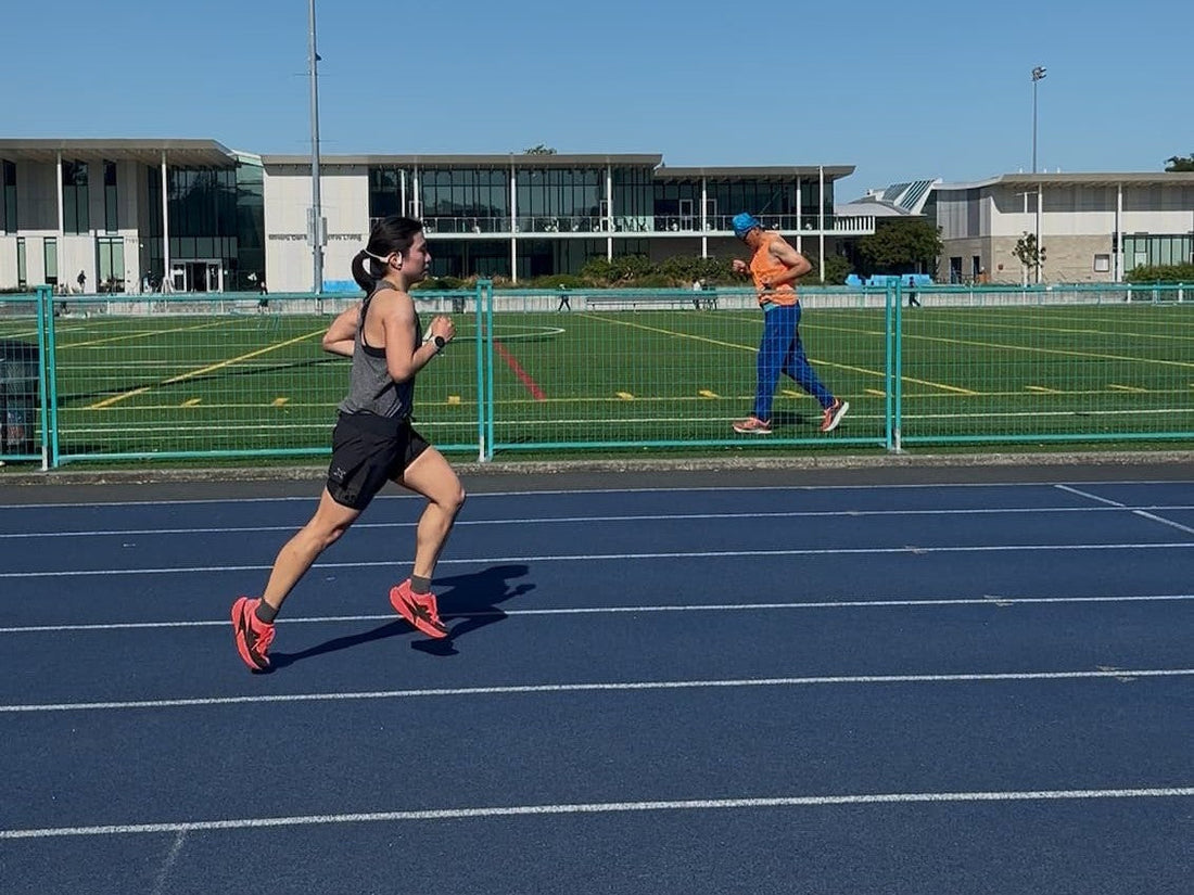 Karla running outdoors on a blue track, with a scenic sky, tying movement to the discipline of calligraphy