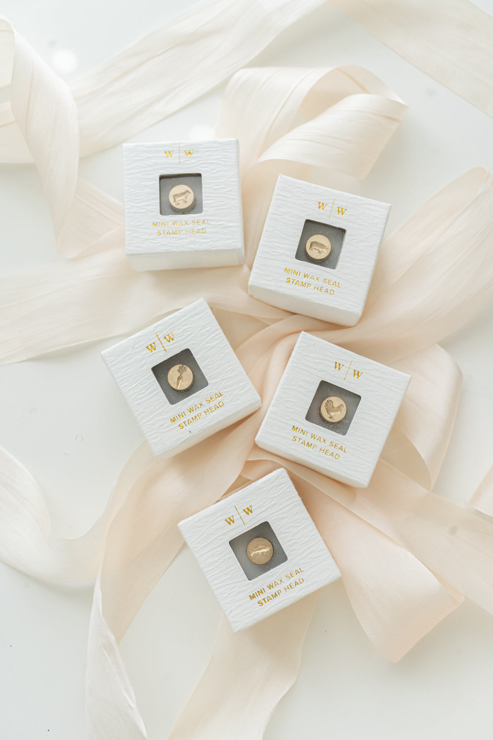 5 mini wax seal heads in a ring-style box, carefully arranged on a blush pink ribbon