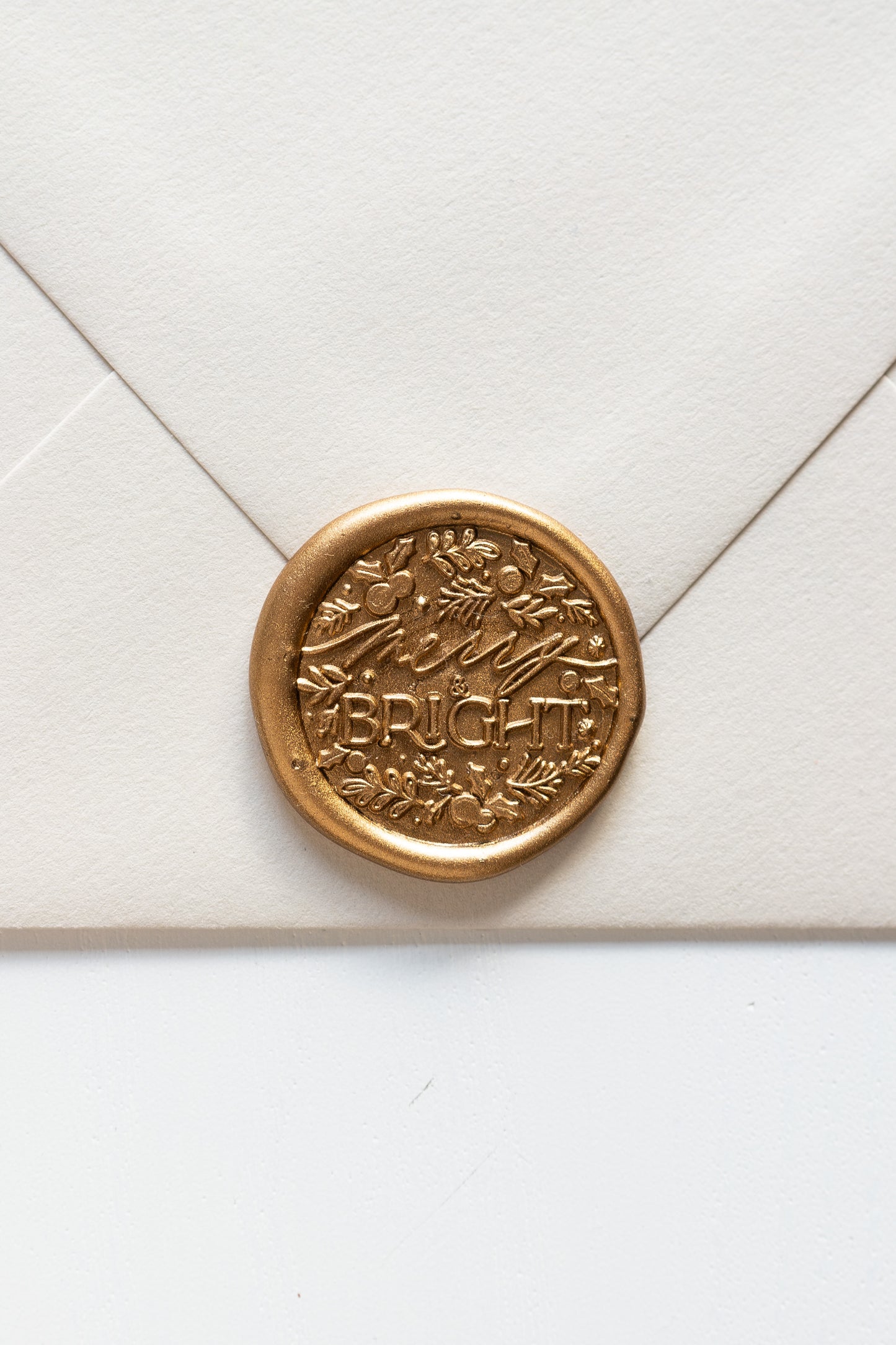 Gold wax seal impression with detailed botanical design on envelope, festive wax seal stationery