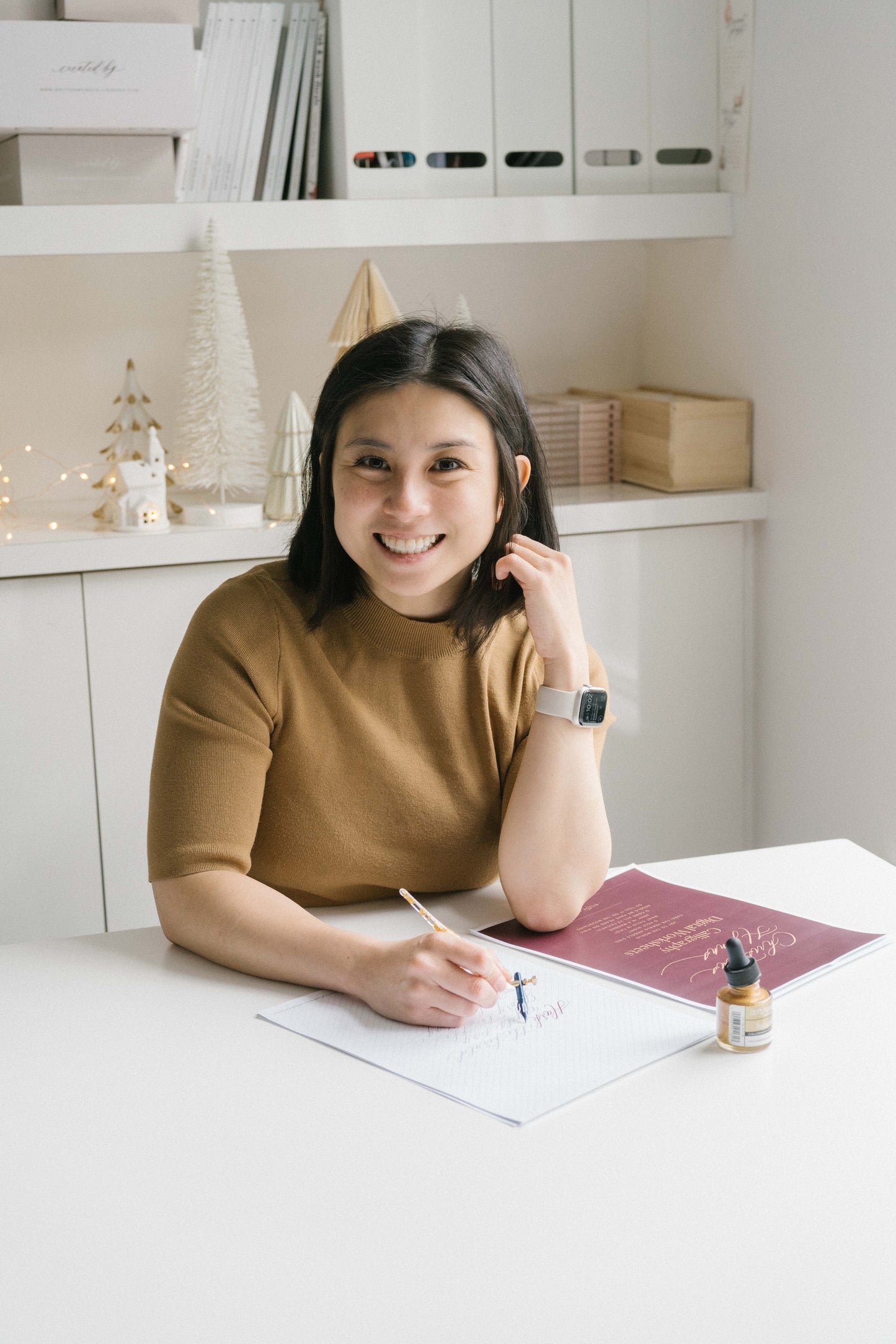 Karla practicing modern calligraphy at desk with oblique pen, ink bottle, and worksheets