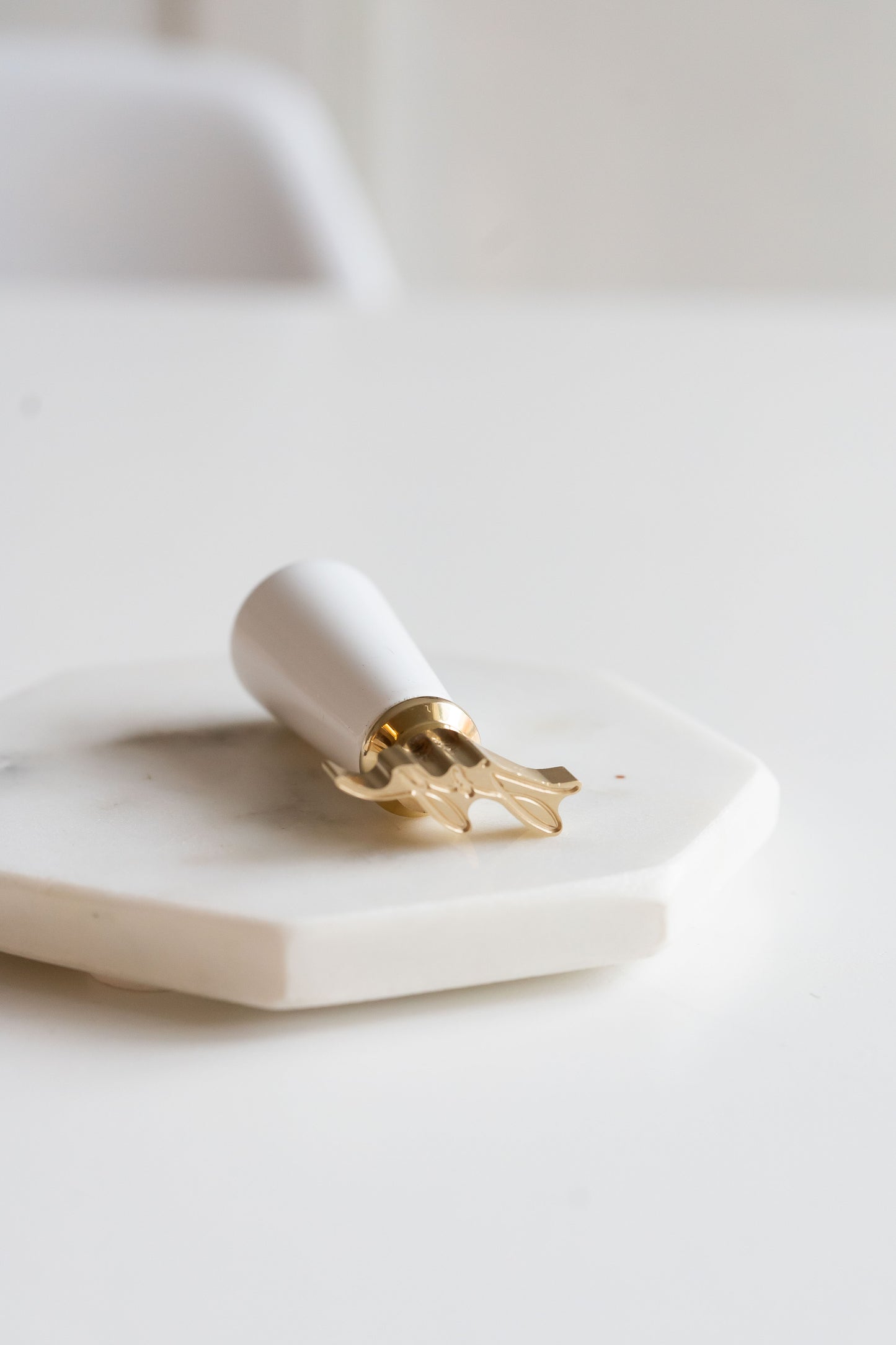 A Holiday wax seal stamp with a white painted wooden handle, engraved with the word Joy on a marble coaster