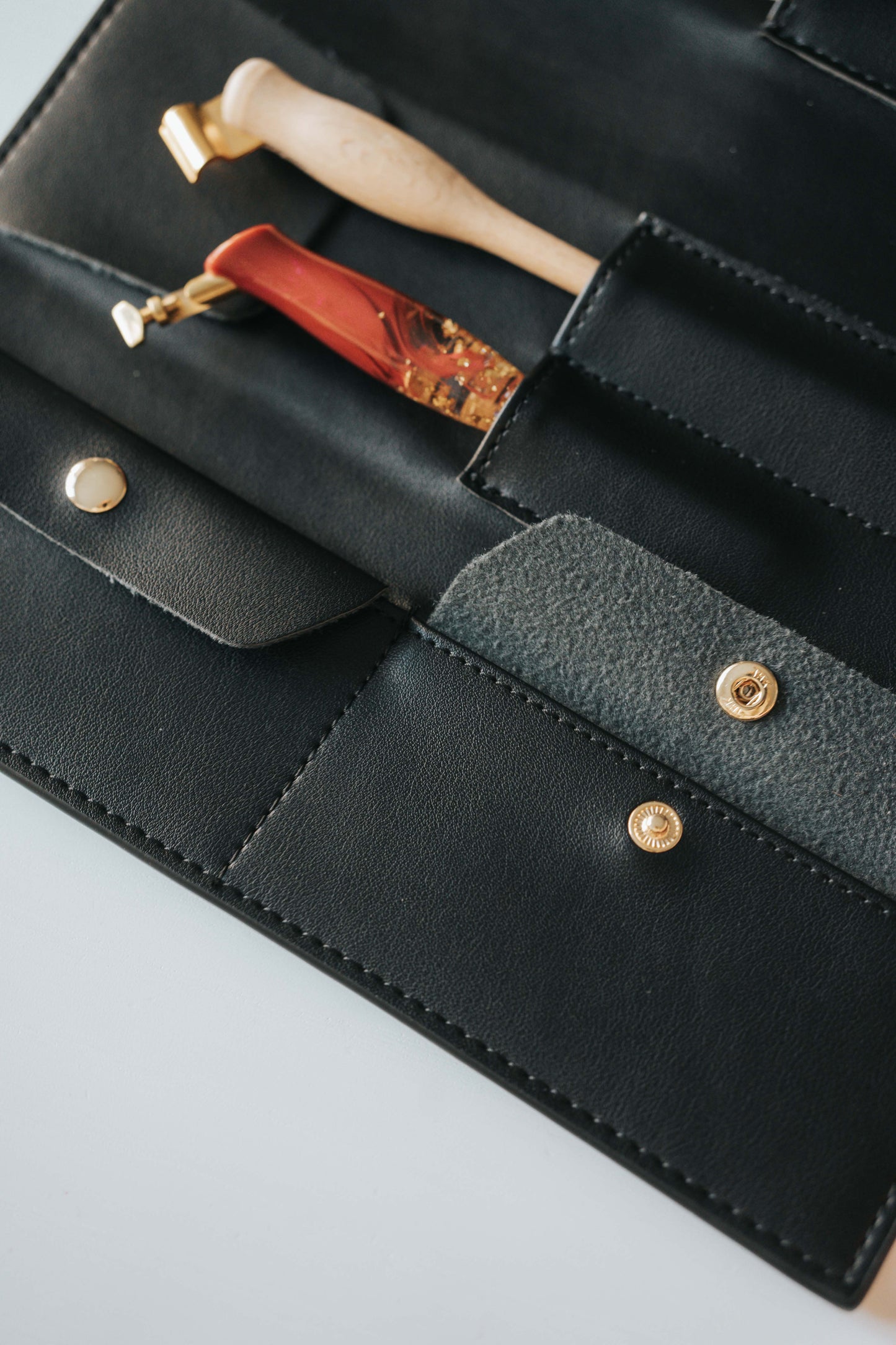 Close-up of black calligraphy pen roll interior with penholder slots and gold snap closure