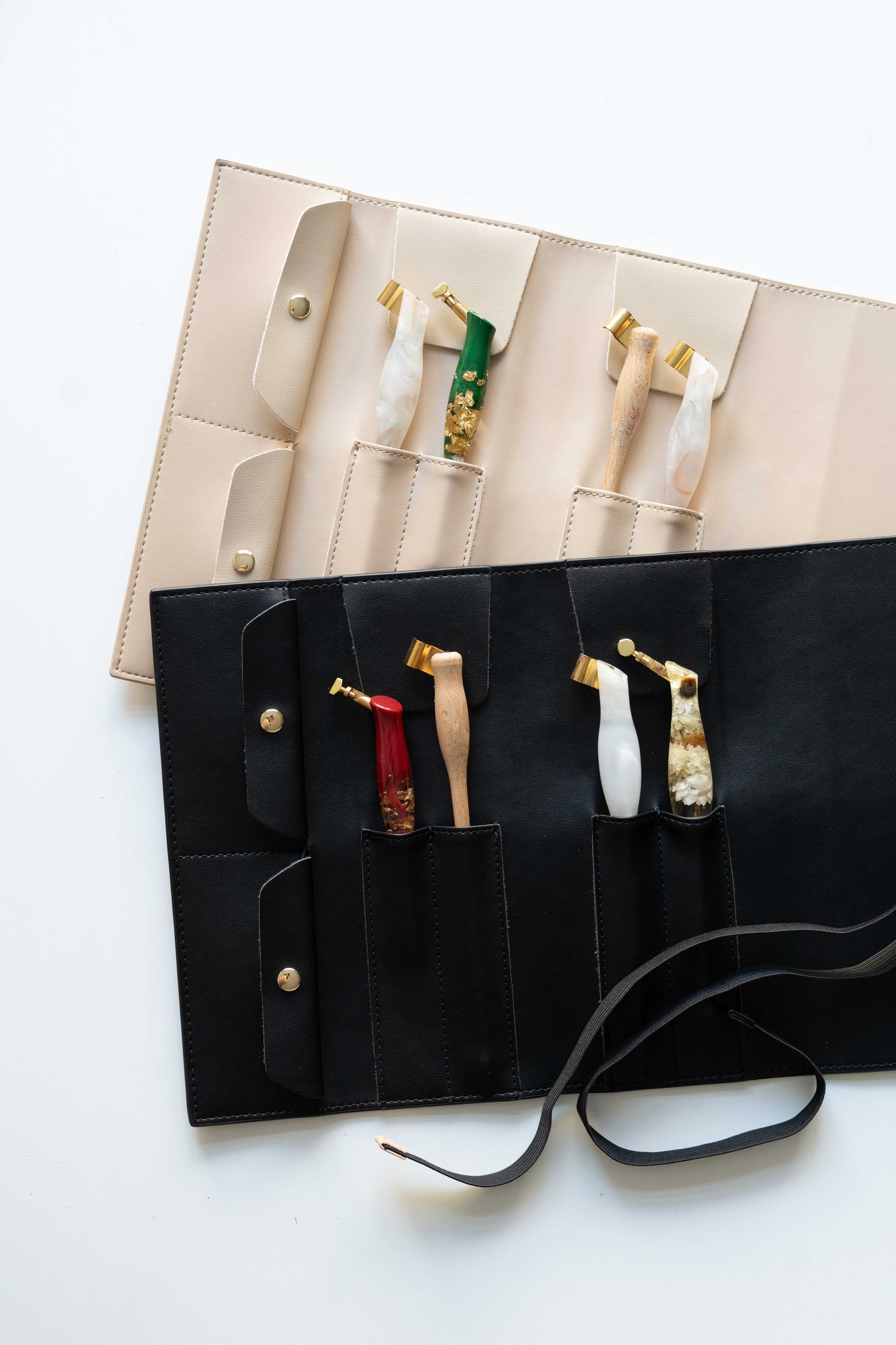 Beige and black calligraphy pen rolls displayed with oblique penholders inside