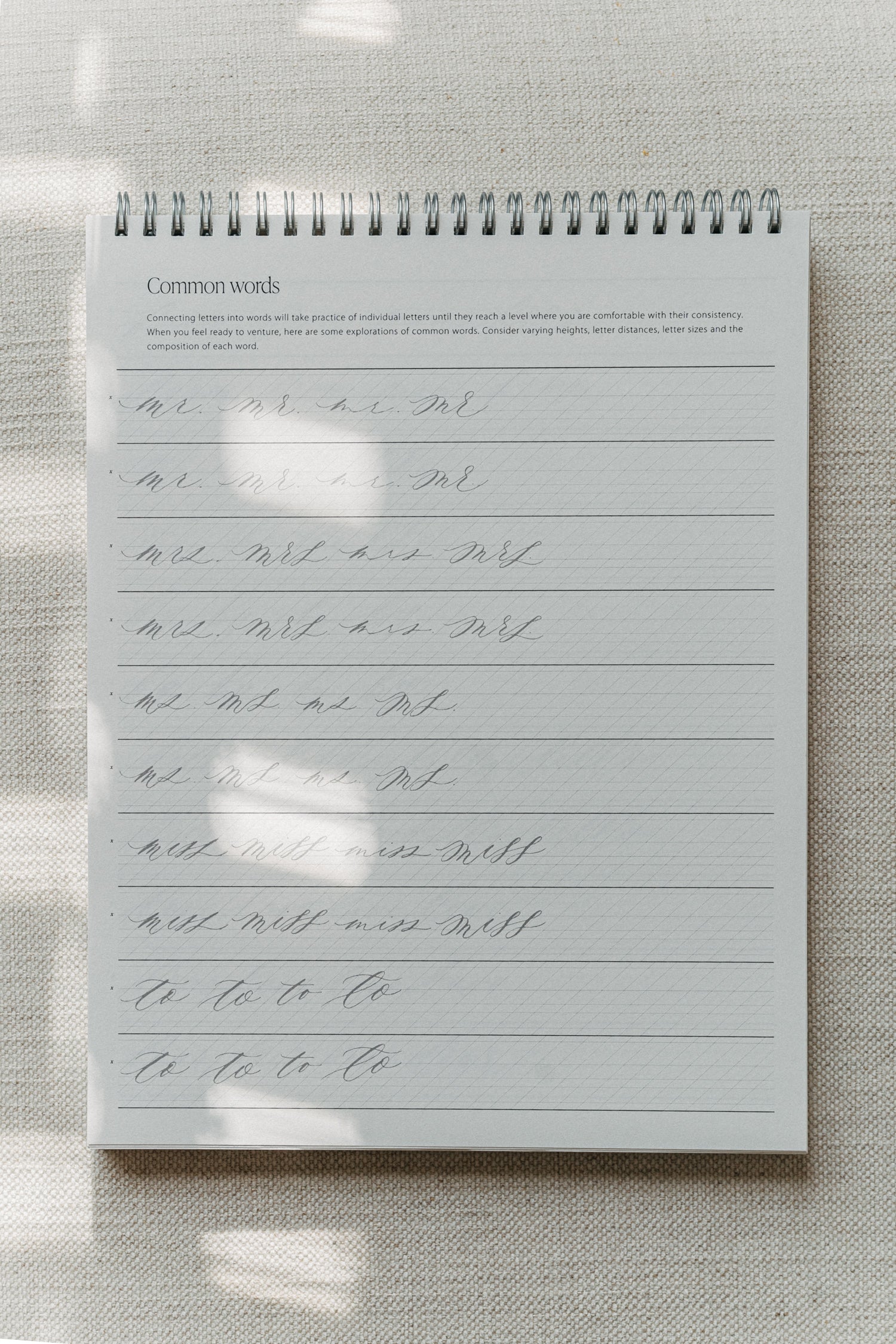 Calligraphy practice pad focusing on writing common words, with exercises for improving letter connections, spacing, and flow