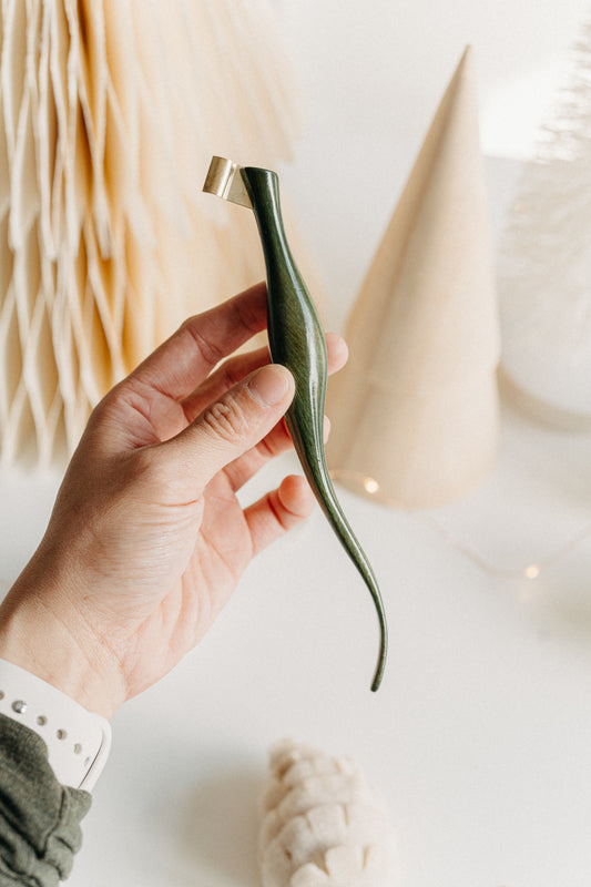 Hand holding a handcrafted curved green lacquer calligraphy penholder, highlighting its elegant shape against soft festive décor.