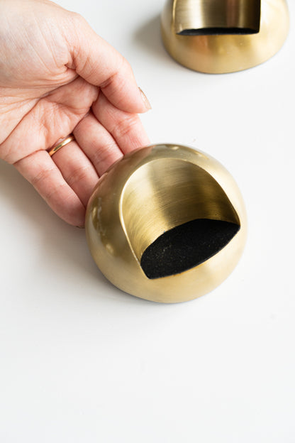 Faux brass inkwell with a round, modern design and black-lined interior, shown held in hand for scale and detail