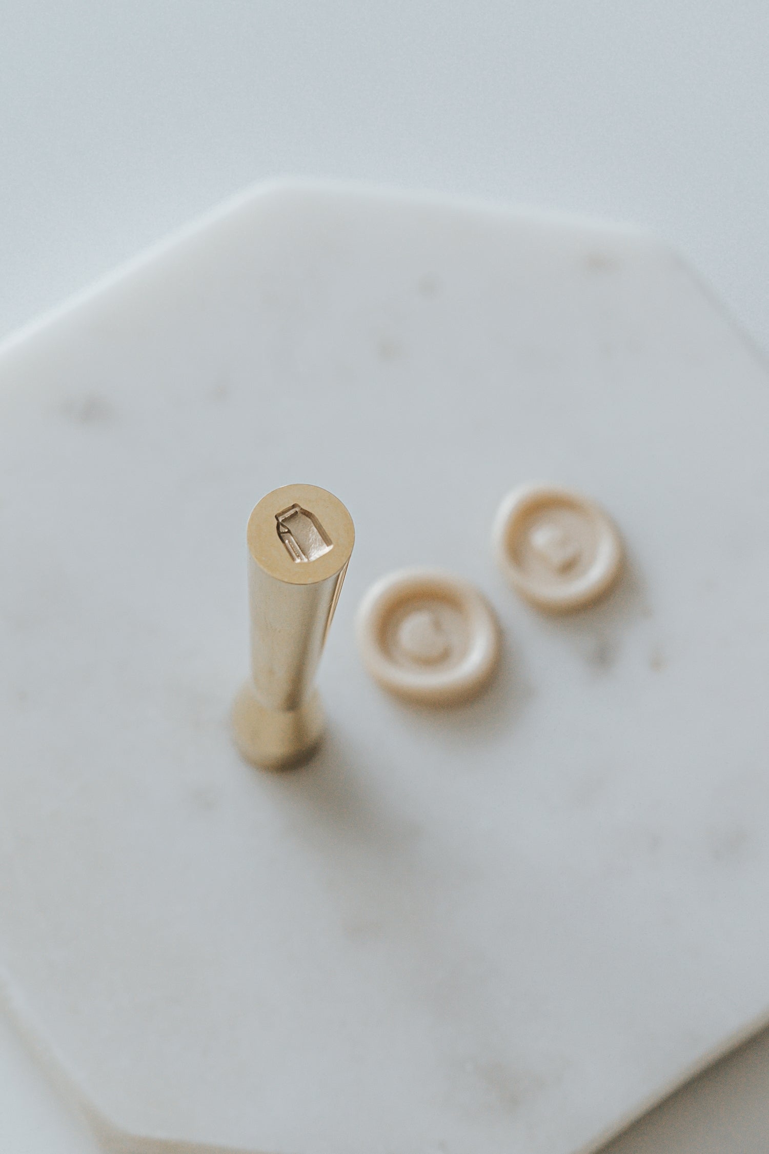 Mini wax seal stamp with a milk carton design, displayed with matching beige wax seals on a white marble surface.