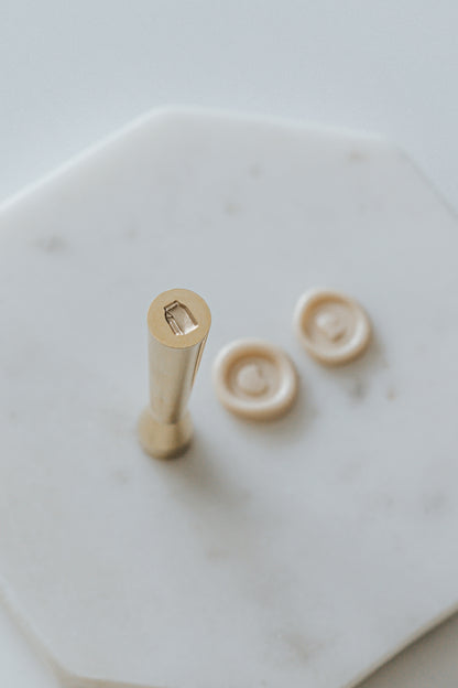 Mini wax seal stamp with a milk carton design, displayed with matching beige wax seals on a white marble surface.