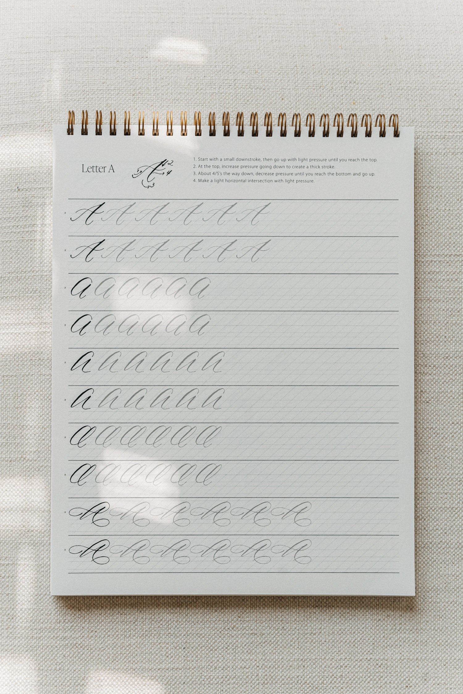 Modern calligraphy practice pad featuring the letter "A" with tracing guides for uppercase letters