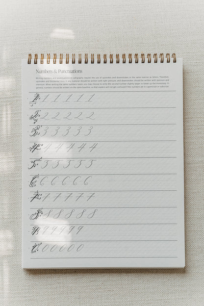 Calligraphy practice pad with drills for numbers and punctuation, focusing on upstrokes and downstrokes