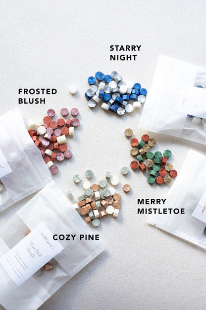 Assorted wax seal beads in four gradients, labeled and spilling from translucent pouches onto a white surface