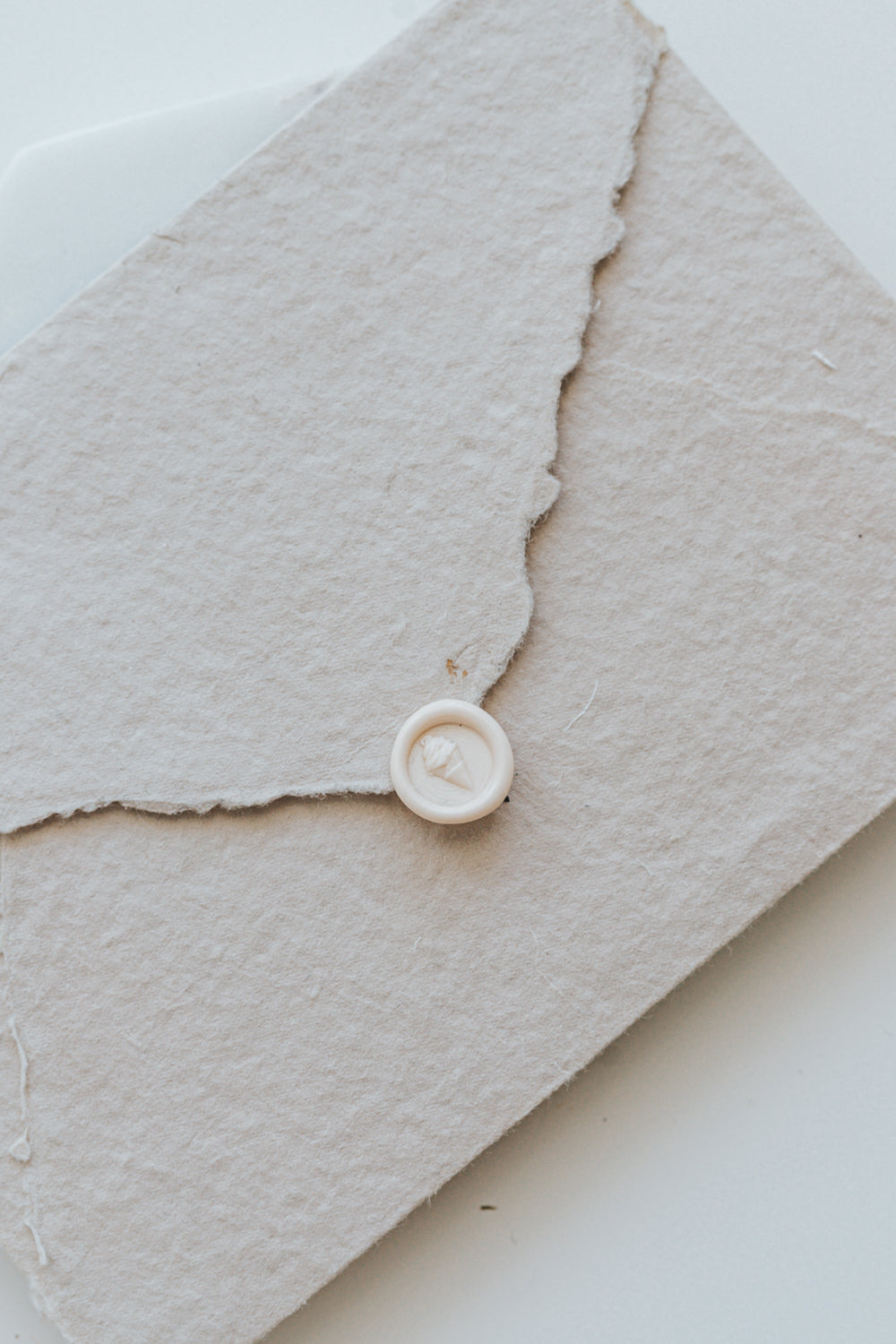 A mini 9mm blush wax seal with a 3D soft serve ice cream design on a textured taupe envelope