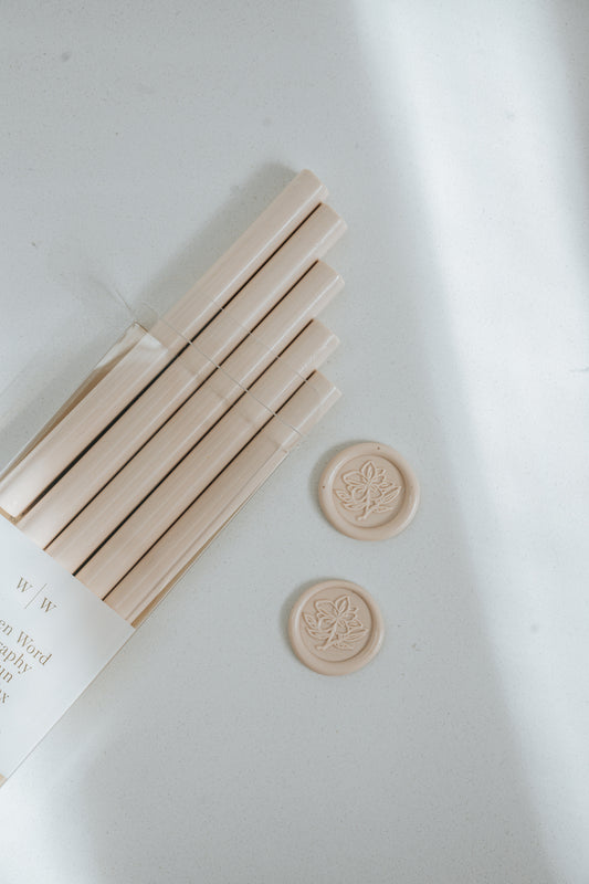 Bundle of Sakura pink wax sticks with two matching wax seals stamped with a magnolia flower design on a light surface