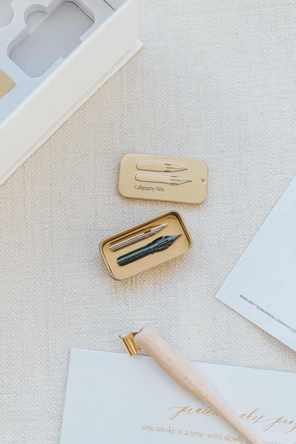 Close-up of a calligraphy nib container with two nibs, part of the Mini Calligraphy Starter Kit, displayed on a textured surface.