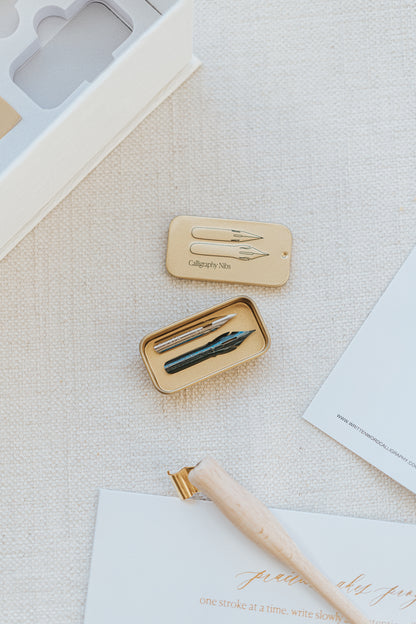 Close-up of a calligraphy nib container with two nibs, part of the Mini Calligraphy Starter Kit, displayed on a textured surface.