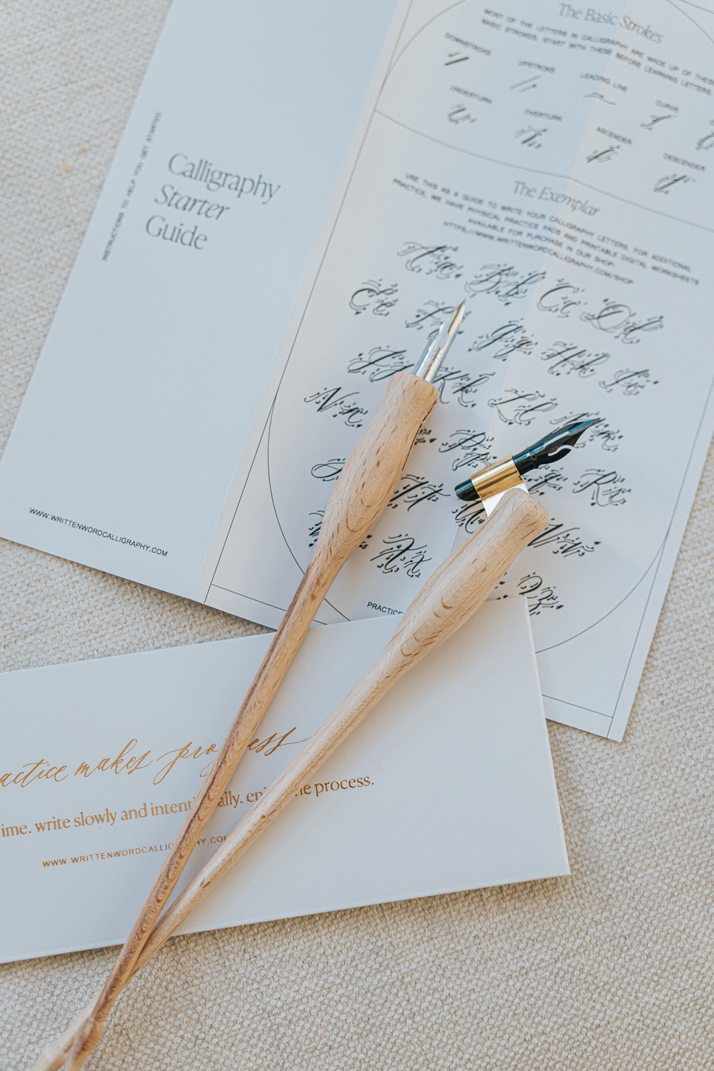 Dual-purpose calligraphy pens with nibs resting on a calligraphy guide, part of the Mini Calligraphy Starter Kit.