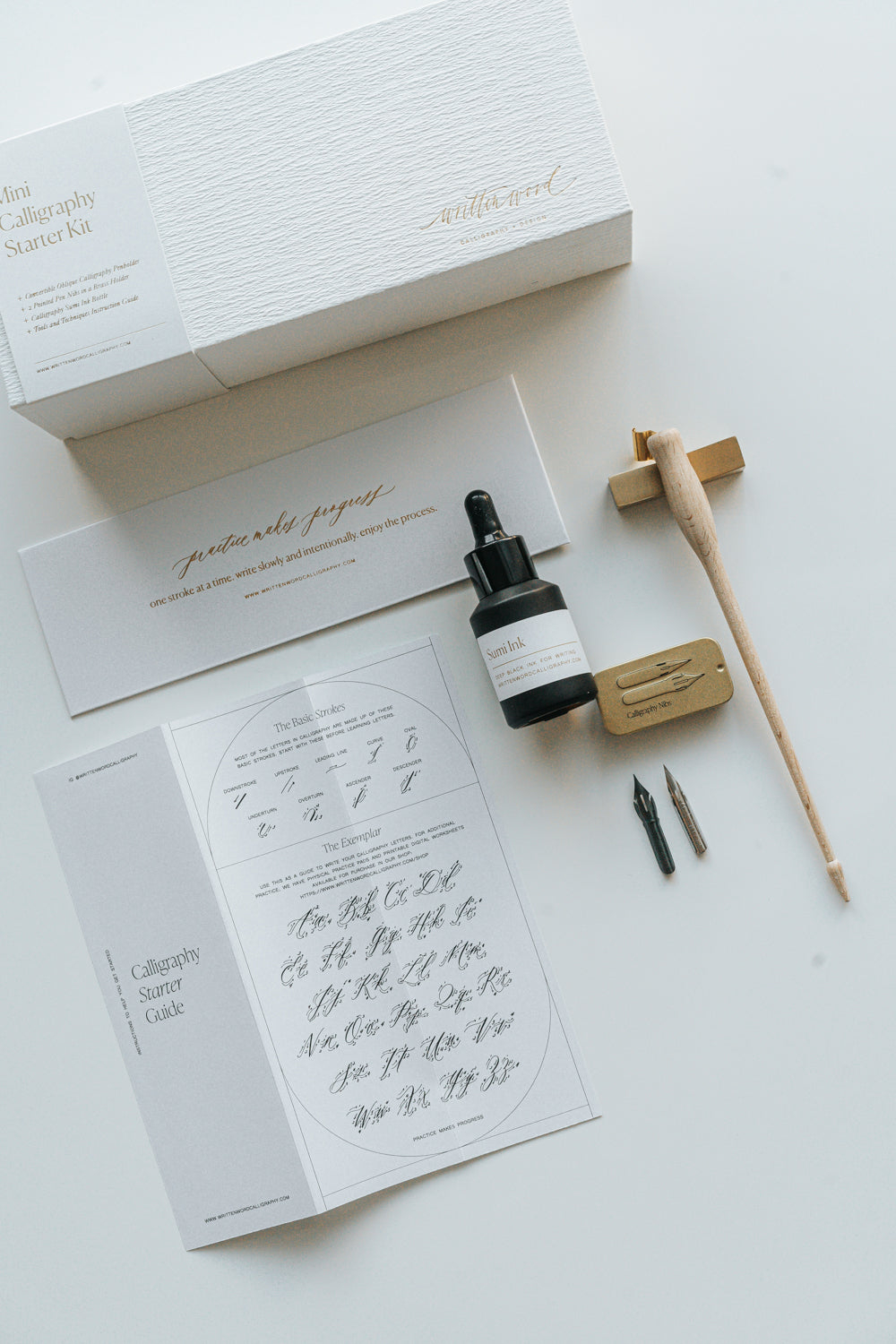 Mini Calligraphy Starter Kit with dual-purpose pen, sumi ink, nibs, brass pen rest, and guide in a luxury gold foil box.