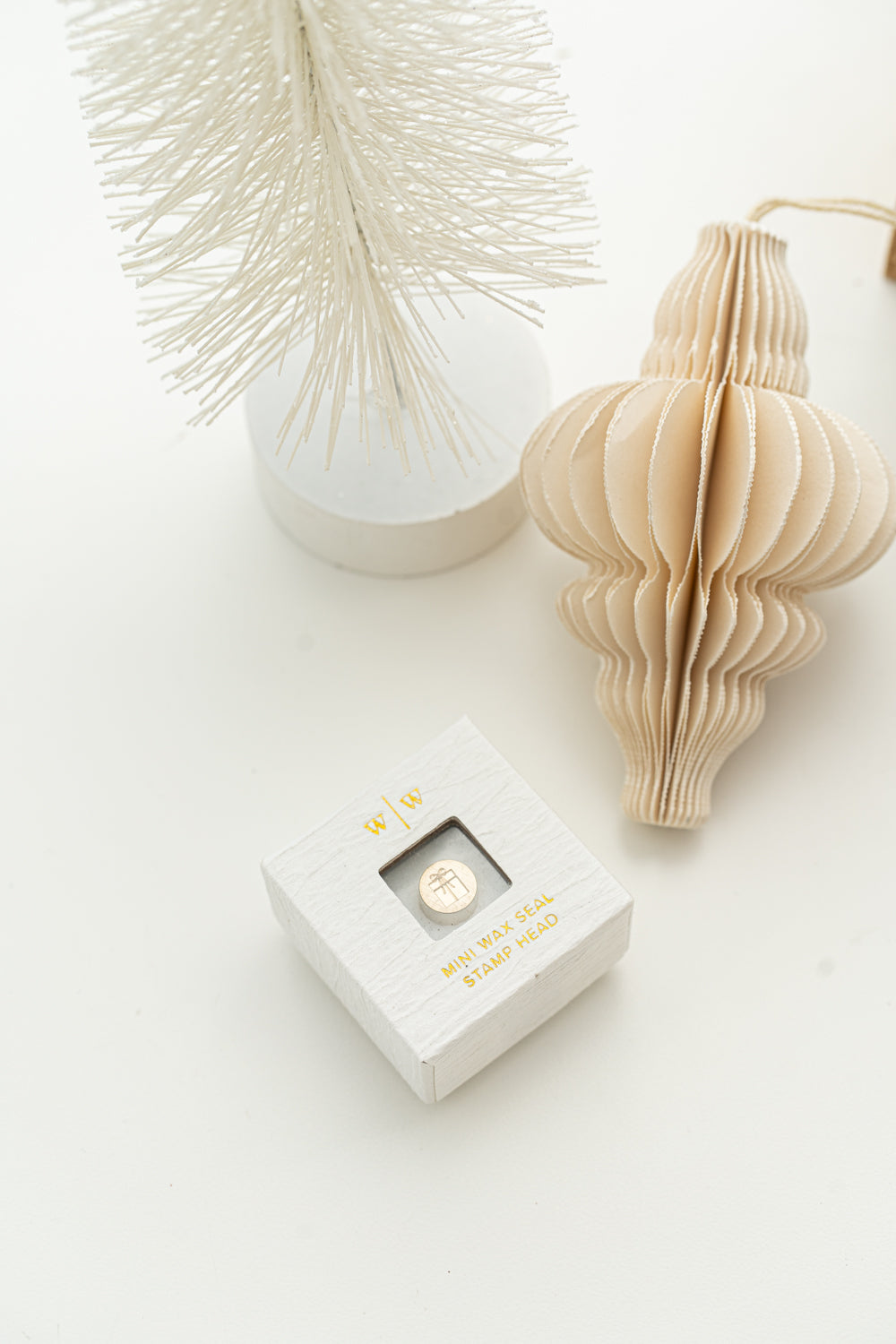 Limited edition wax seal stamp of a 3d illustration of a wrapped present with a small ribbon bow in a white ring style box.