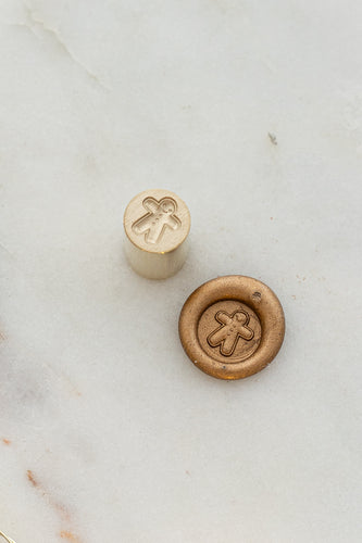 Close-up of festive wax seal stamp featuring a gingerbread man design in gold wax, from Written Word Calligraphy’s Holiday Collection.