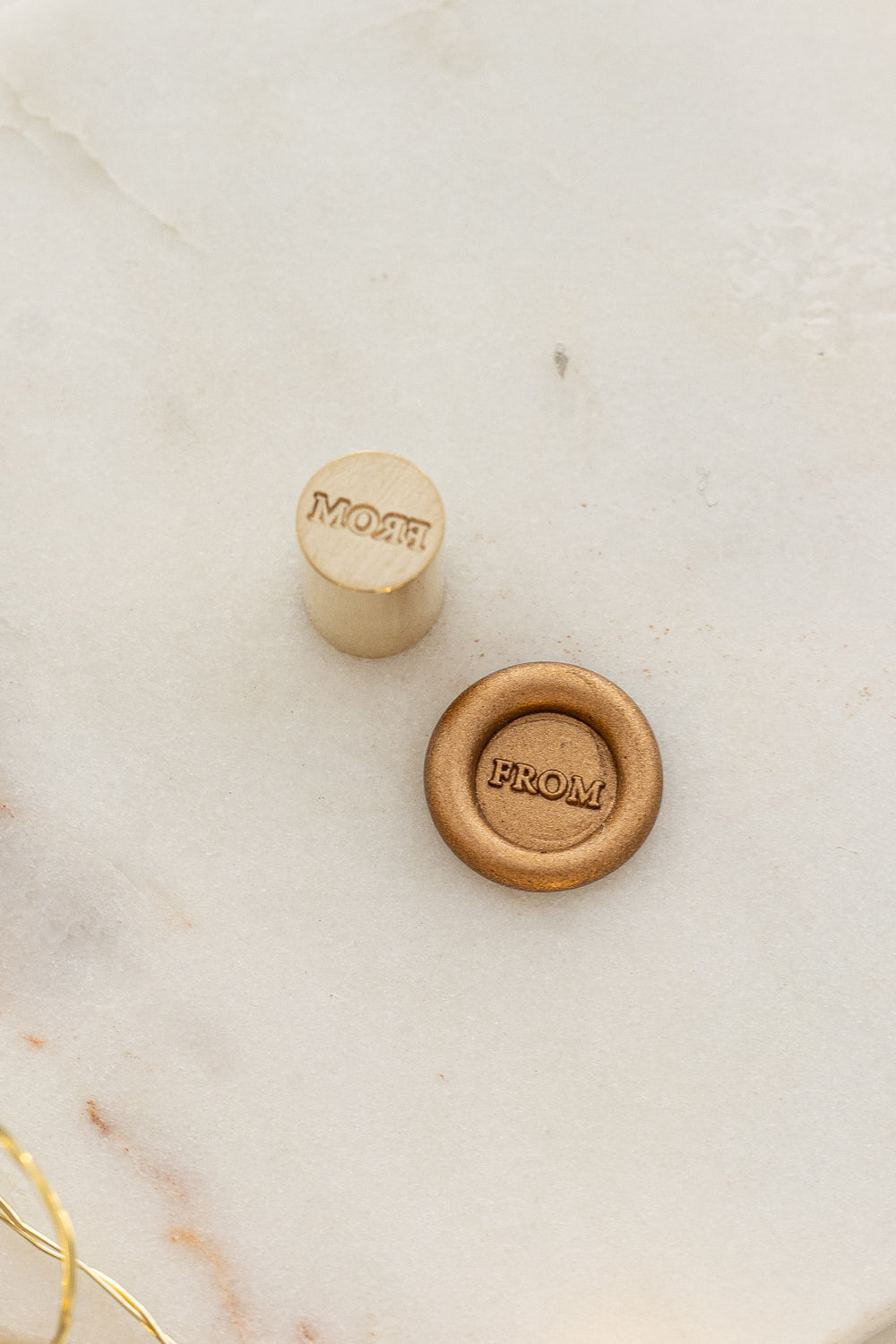 Close-up of mini wax seal stamp with “FROM” design in gold wax, part of Written Word Calligraphy’s Holiday Collection.