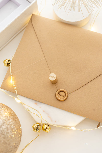 Mini wax seal stamp with “FROM” design in gold wax on a kraft envelope, part of Written Word Calligraphy’s Holiday Collection.