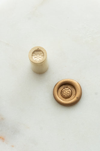 Close-up of festive wax seal stamp featuring a round ornament design in gold wax, from Written Word Calligraphy’s Holiday Collection.