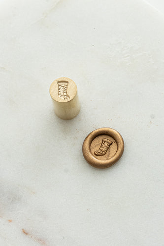 Close-up of mini wax seal stamp with Christmas stocking design in gold wax, part of Written Word Calligraphy’s Holiday Collection.