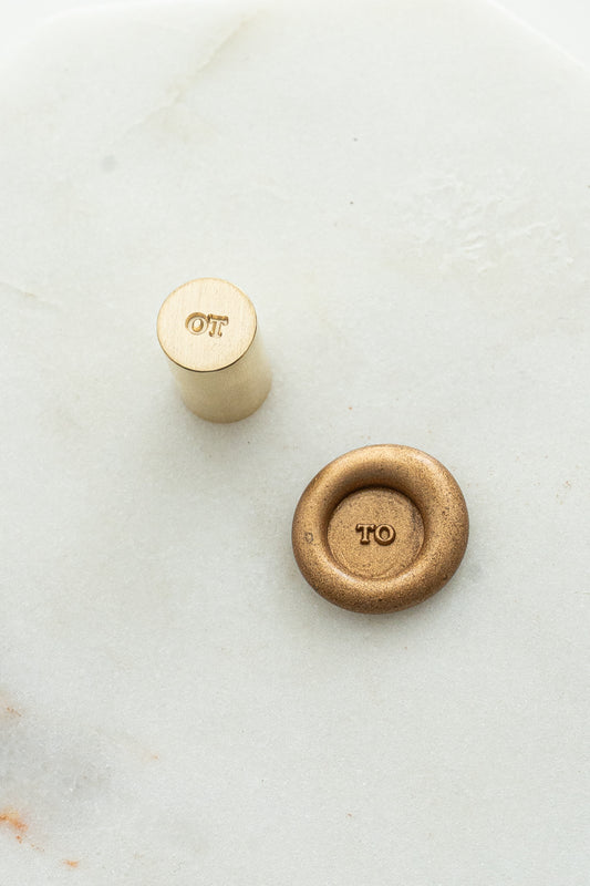 Close-up of mini wax seal stamp with “TO” design in gold wax, part of Written Word Calligraphy’s Holiday Collection.