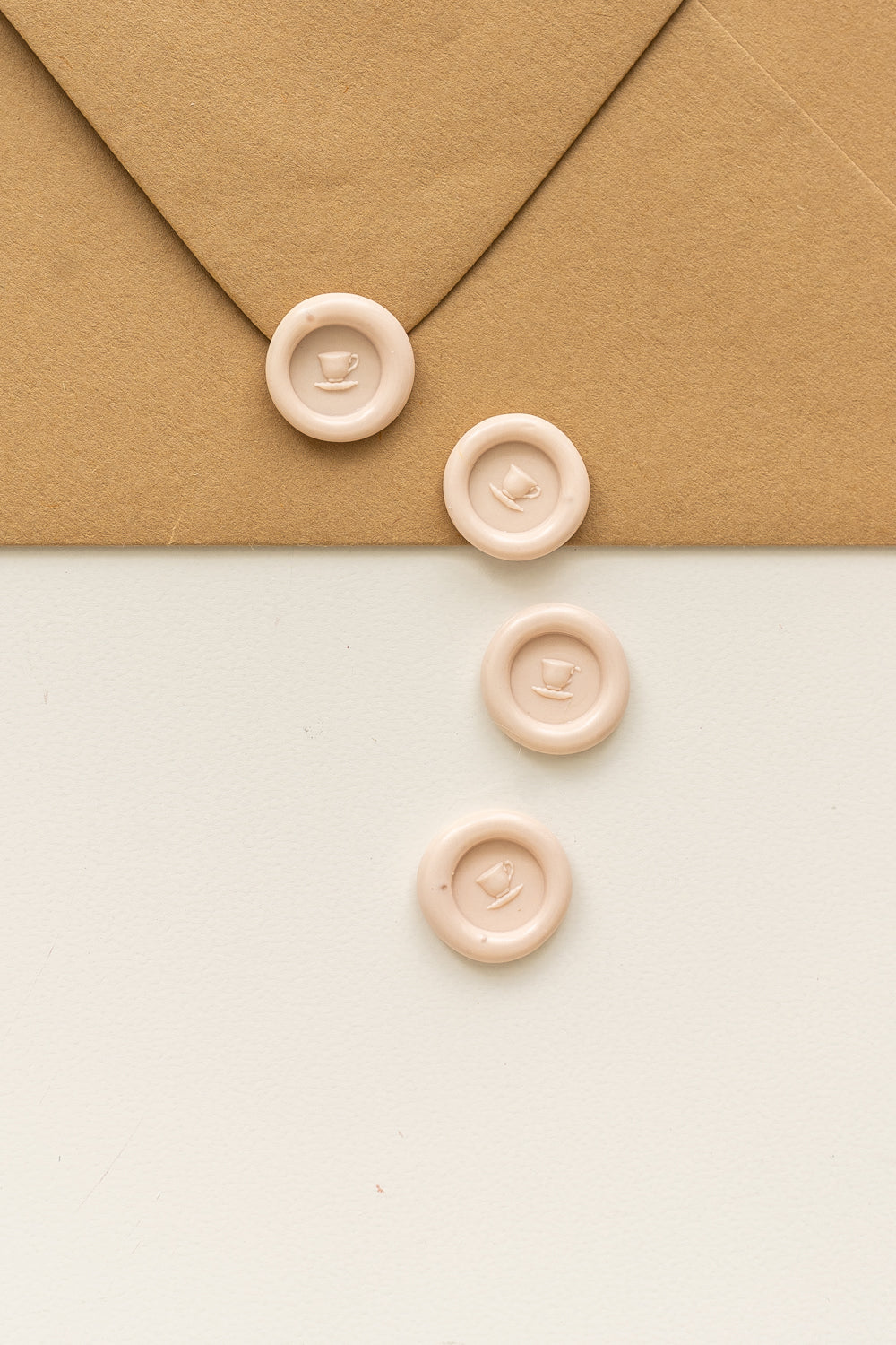 4 blush mini wax seals with a 3D tea cup design on a kraft envelope and white surface