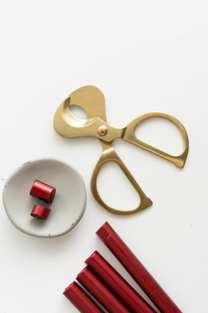 Gold scissors with lunar red sealing wax sticks on a white background