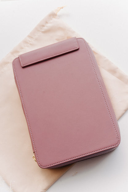 A dusty rose calligraphy travel kit on a beige dust bag on a white surface