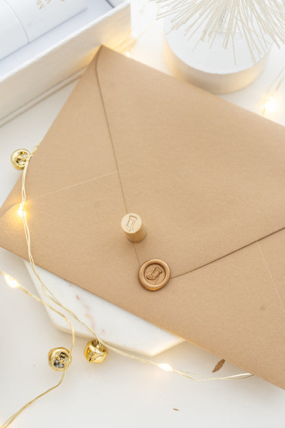 Mini wax seal stamp with Christmas stocking design in gold wax on a kraft envelope, part of Written Word Calligraphy’s Holiday Collection.