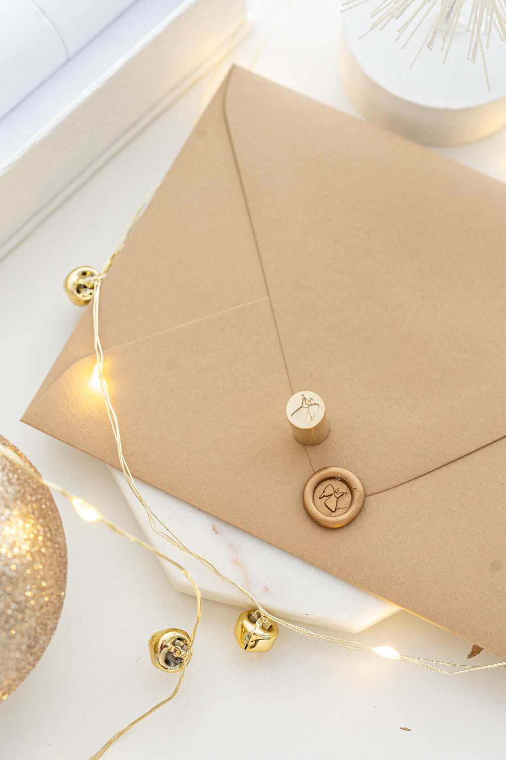 Close-up of elegant wax seal stamp featuring a gingerbread house design in gold wax, from Written Word Calligraphy’s Holiday Collection.