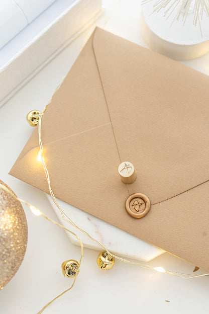 Close-up of elegant wax seal stamp featuring a gingerbread house design in gold wax, from Written Word Calligraphy’s Holiday Collection.