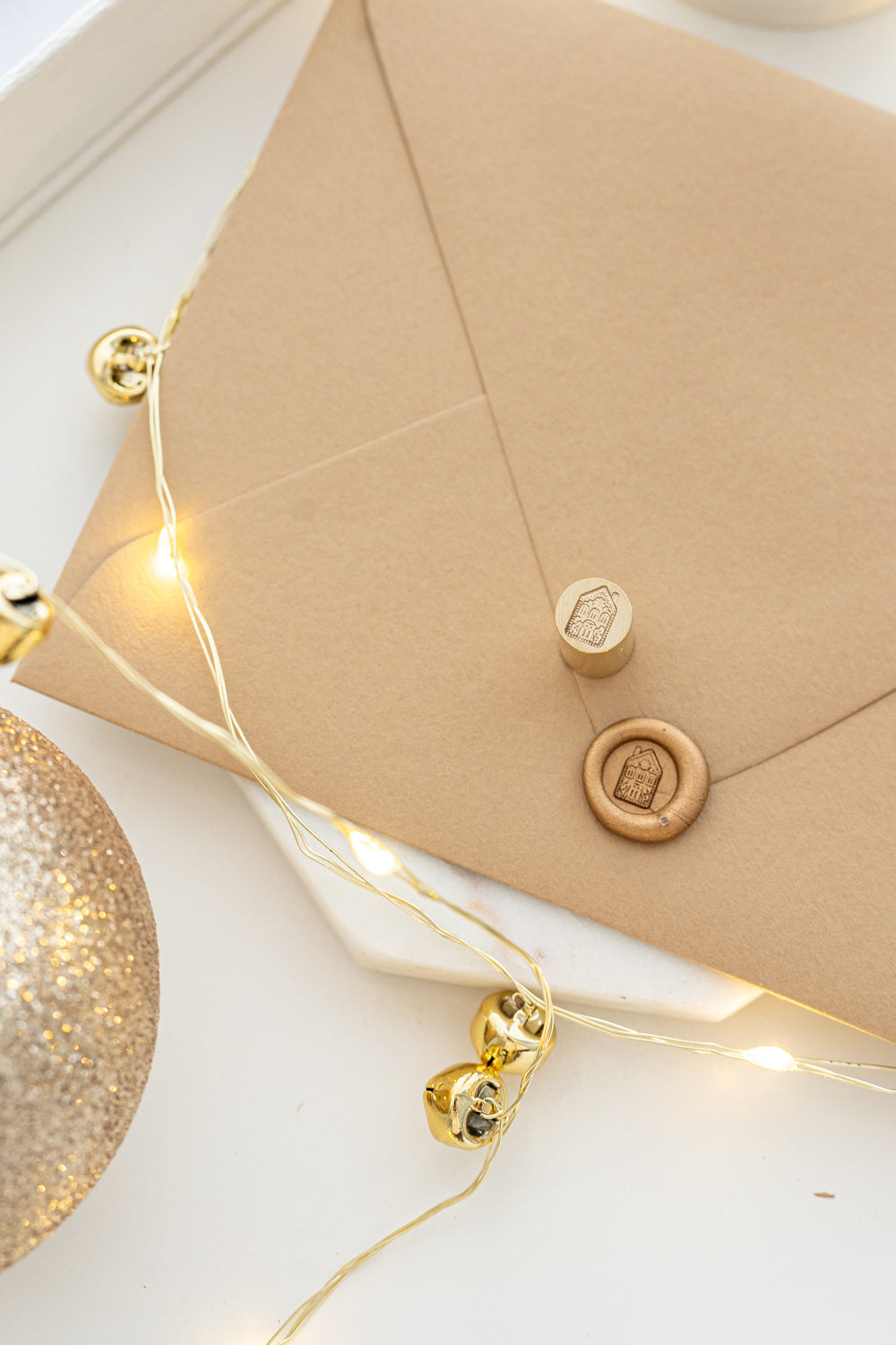 Classic holiday mini wax seal stamp with gingerbread house design in gold wax on a kraft envelope, part of Written Word Calligraphy’s Holiday Collection.