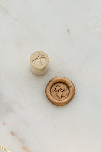 Close-up of elegant wax seal stamp featuring an angel design in gold wax, from Written Word Calligraphy’s Holiday Collection.