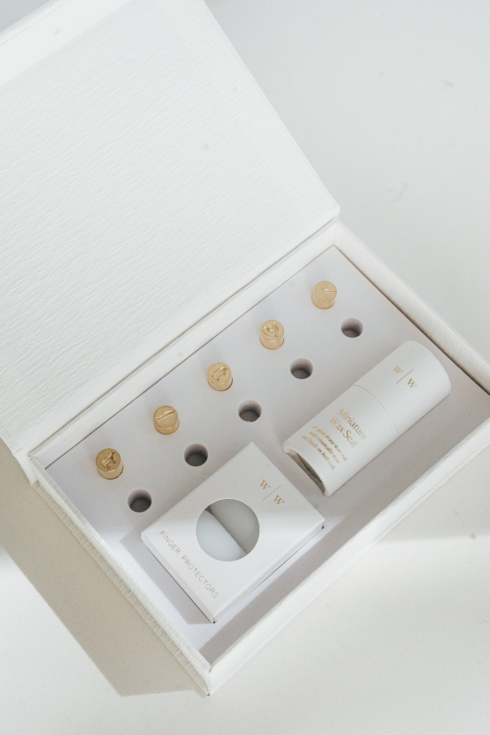 5 mini brass wax seal stamp heads featuring a cow, pig, carrot, chicken, and fish designs, neatly arranged in a keepsake white box with finger protectors and stamp handle