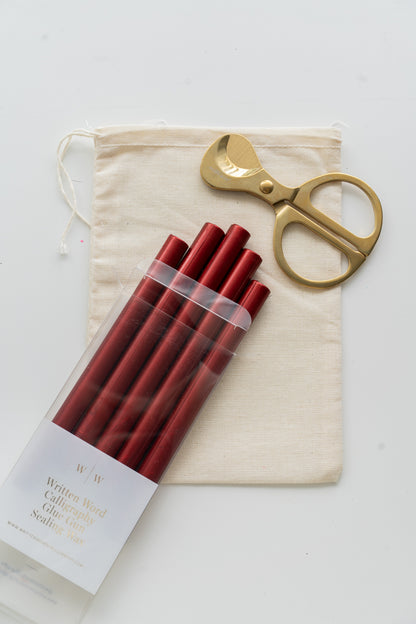 Set of lunar red sealing wax sticks with a pair of scissors and a drawstring bag on a white background