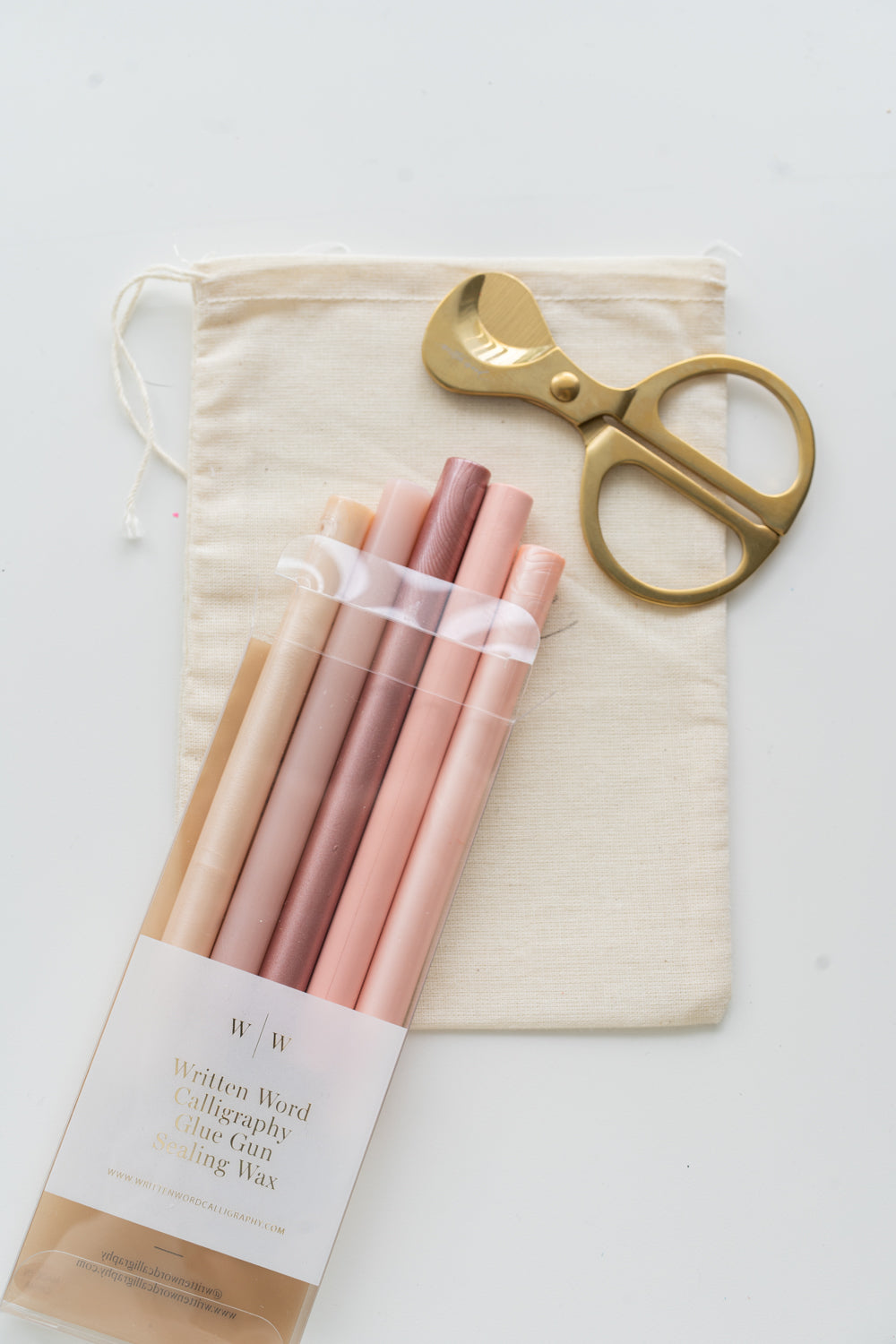 Set of afternoon rosé sealing wax sticks with a pair of scissors and a drawstring bag on a white background