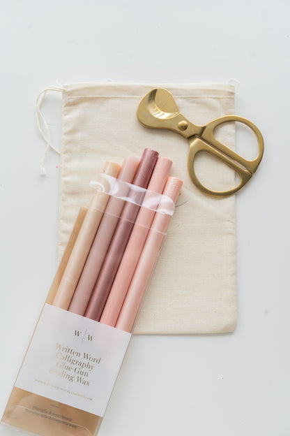 Set of afternoon rosé sealing wax sticks with a pair of scissors and a drawstring bag on a white background