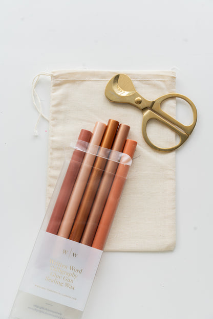 Set of golden hour sealing wax sticks with a pair of scissors and a drawstring bag on a white background