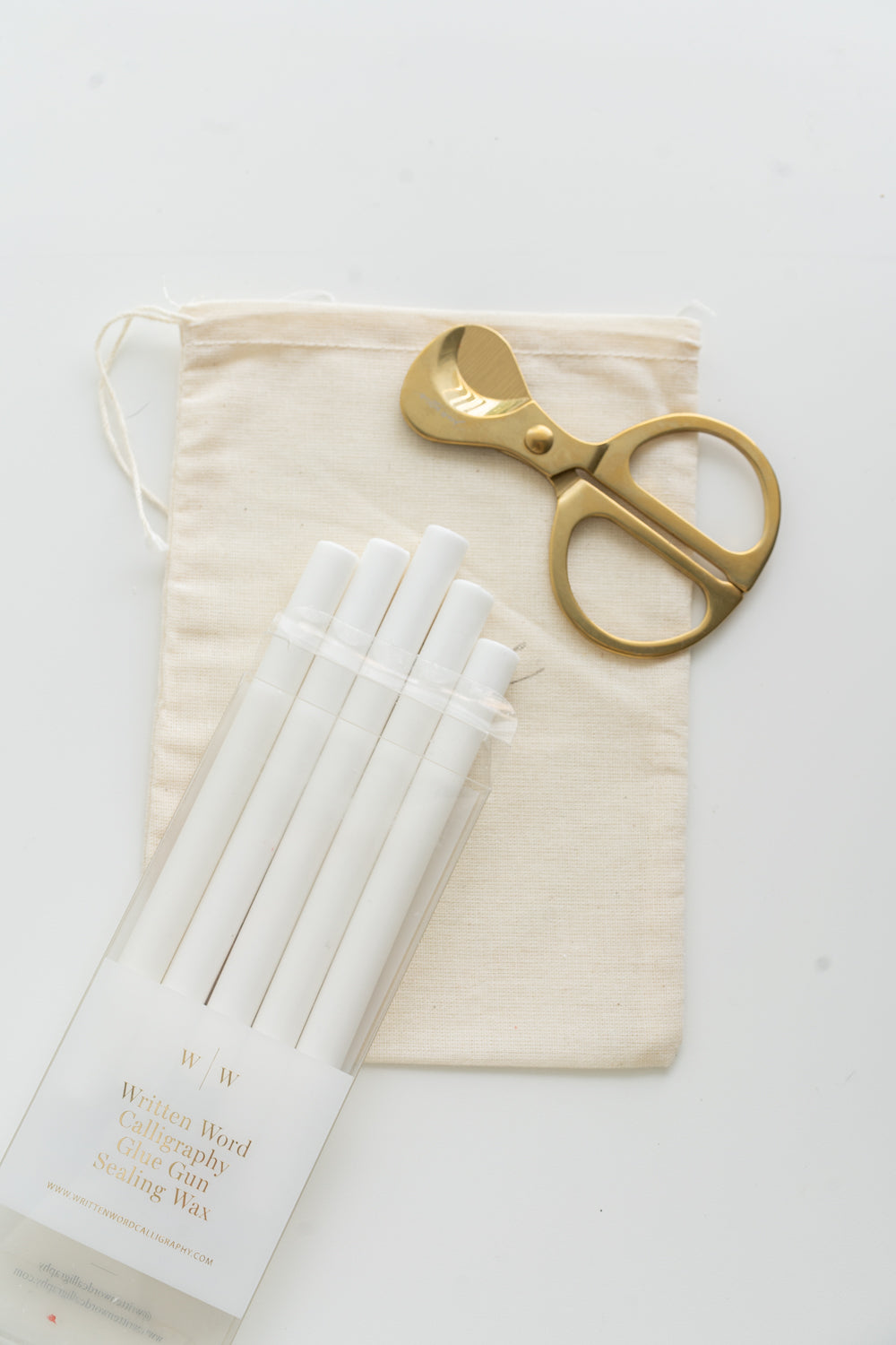 Set of white sealing wax sticks with a pair of scissors and a drawstring bag on a white background
