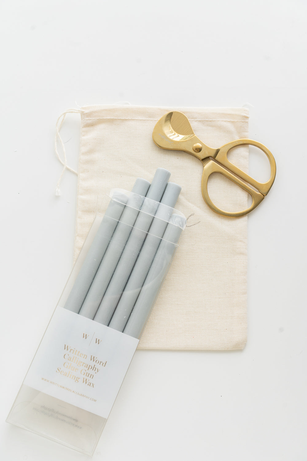 Set of gray sealing wax sticks with a pair of scissors and a drawstring bag on a white background