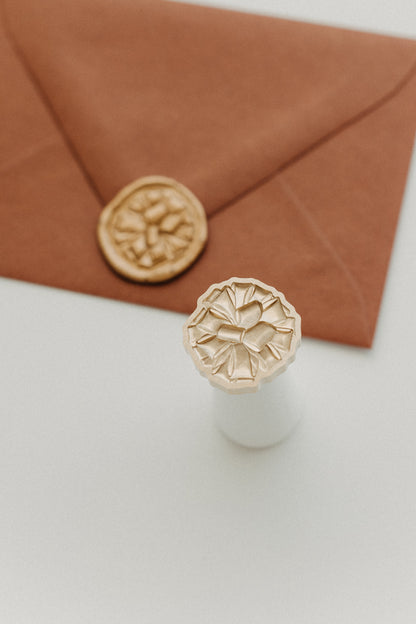Gift bow wax seal stamp with gold wax seal on rust terracotta envelope, holiday gift wrapping