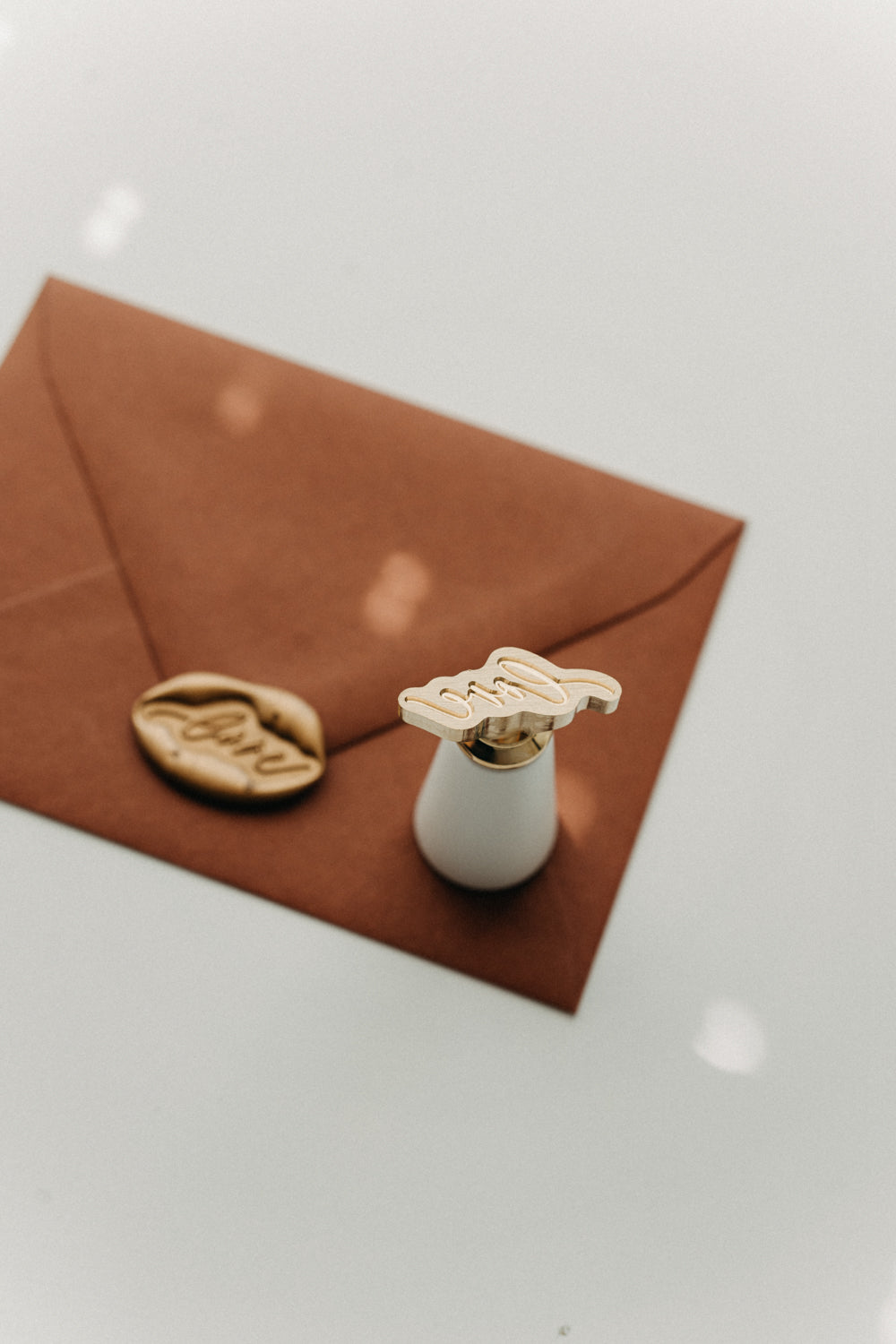 Brass “love” wax seal stamp and gold wax seal displayed on a warm brown envelope.