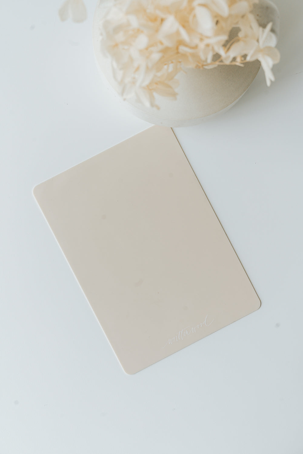 Mini silicone mat for wax sealing on white surface with dried florals in bowl